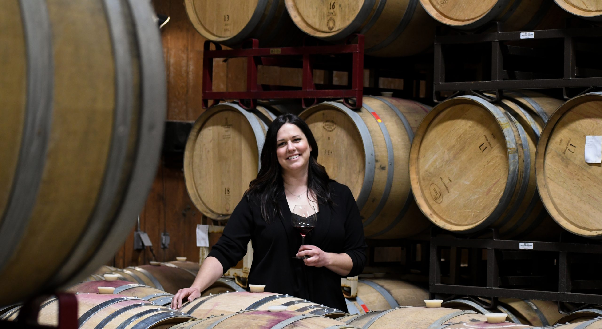 Winemaker Kristin Bryden holding a glass of wine in the barrel room